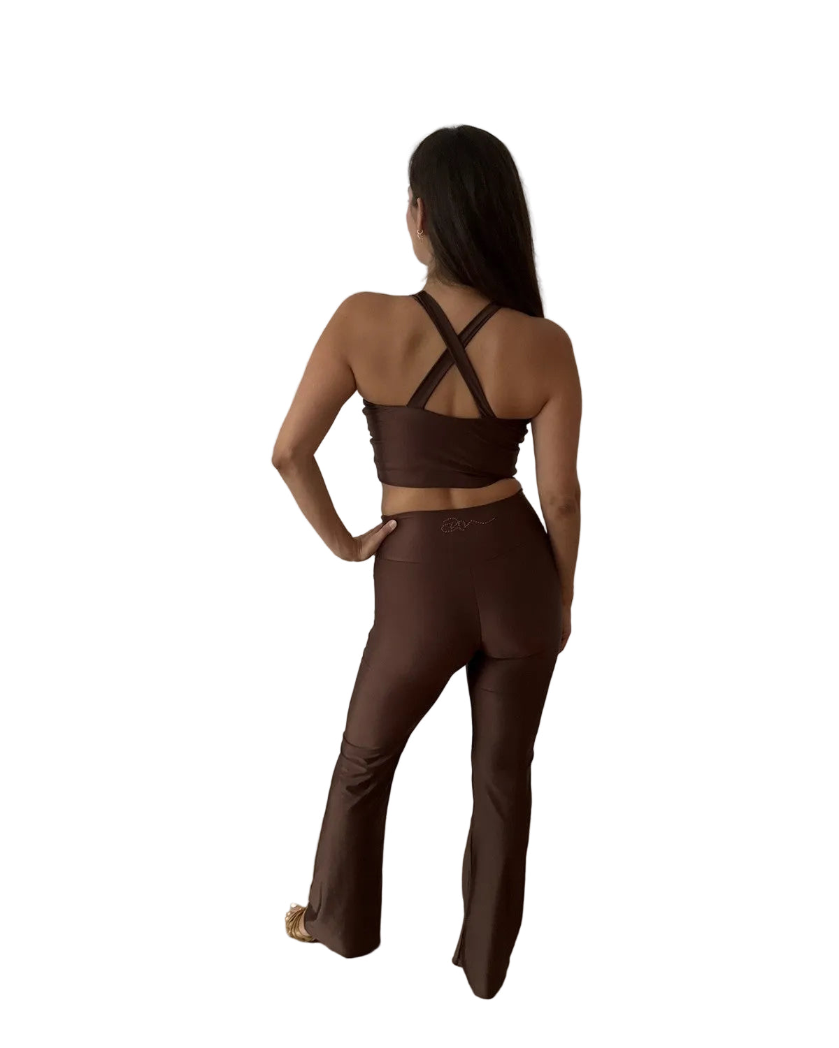 A woman stands with her back to the camera wearing a matching dark brown activewear set consisting of a strappy halter crop top and high-waisted flared leggings dance set wear
