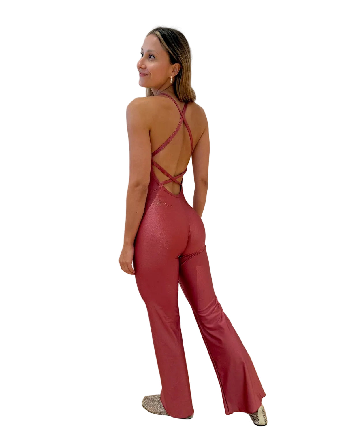 A woman wearing a shiny dusty rose red glitter jumpsuit with a strappy open back.